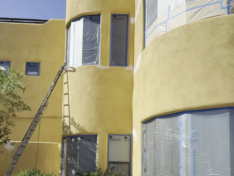 Curved stucco elevations of Fountain Hills AZ custom home masked for spraying and after fresh gold exterior paint